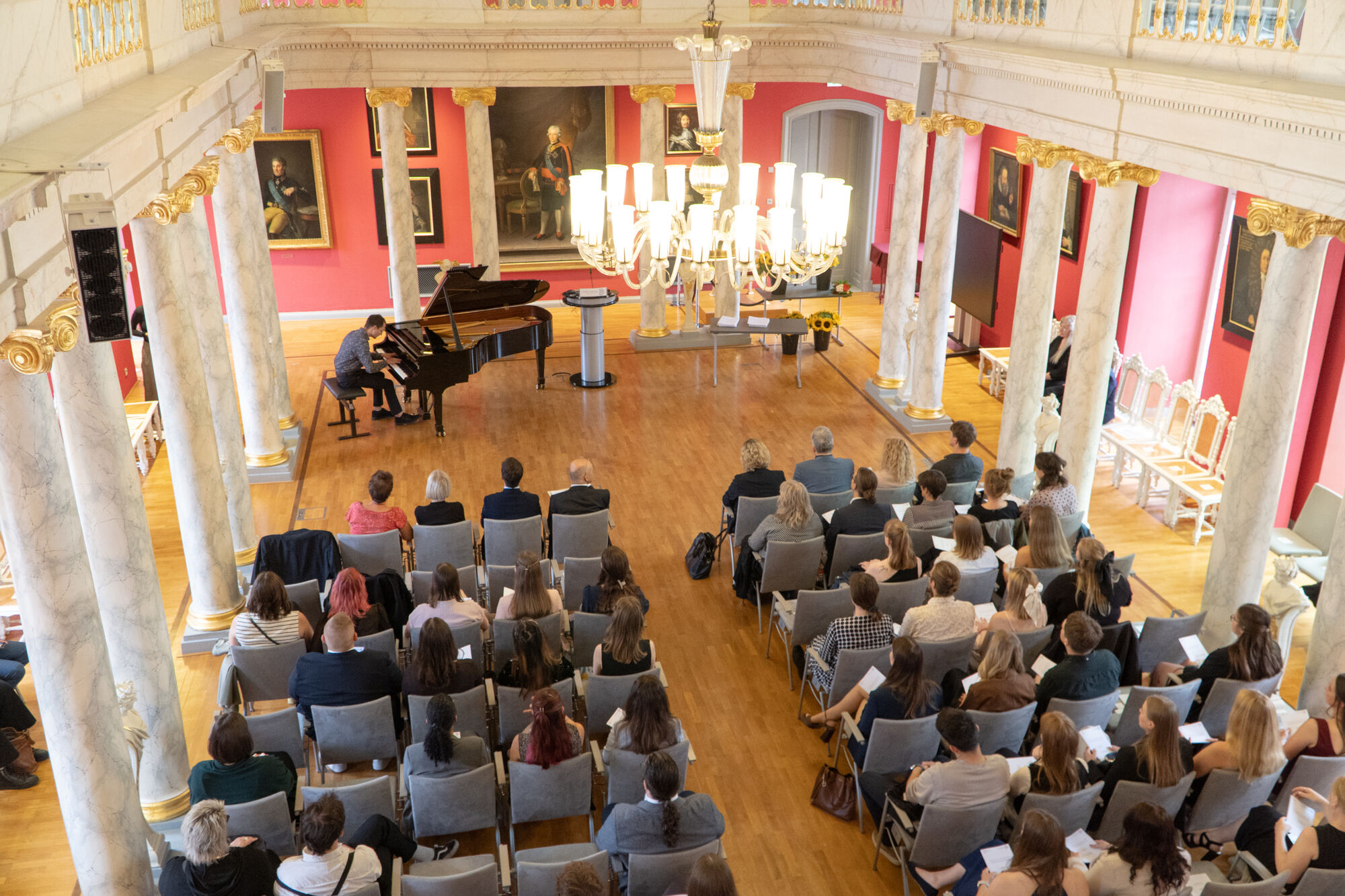 Blick von der Empore der Aula auf die Absolventinnen und Absolventen.