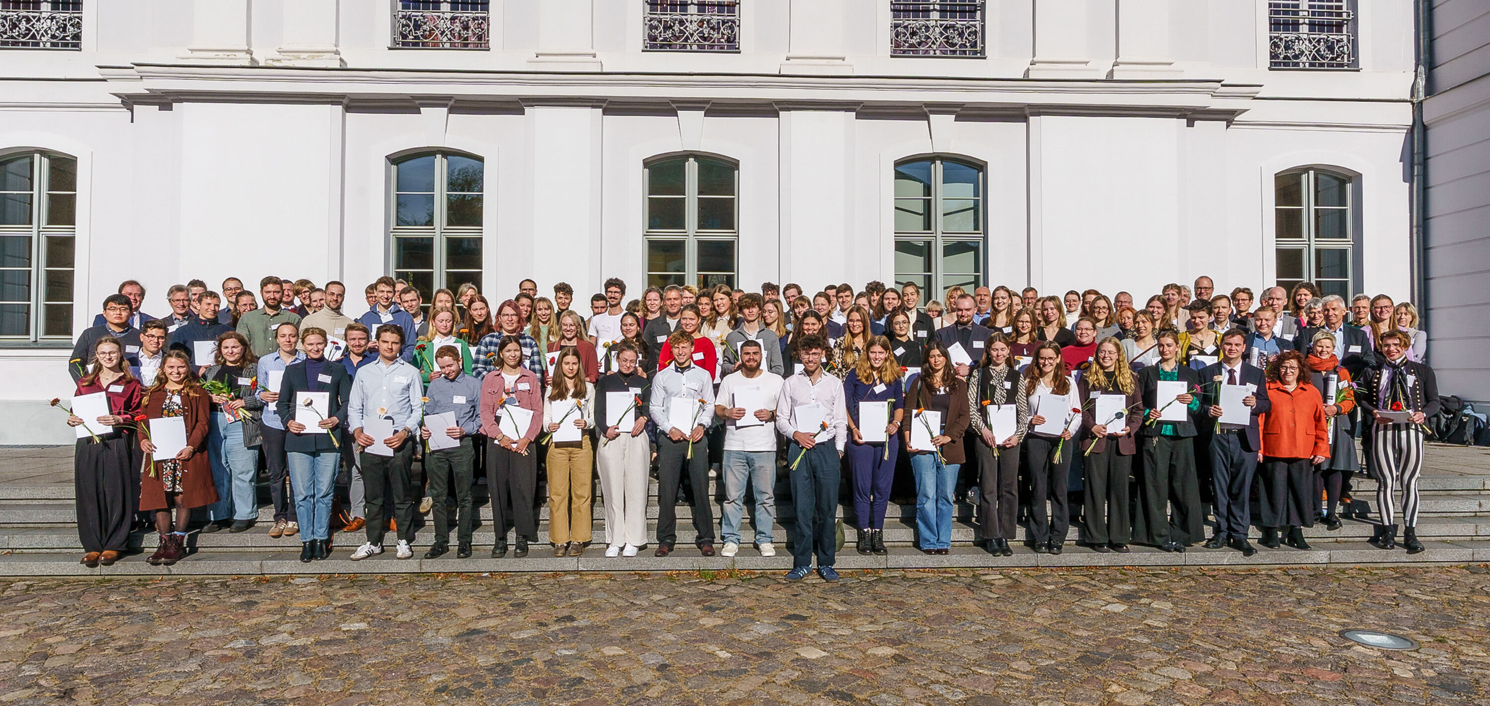 Gruppenbild der Förderer und Empfänger*inn des Deutschlandstipendiums vor dem Hauptgebäude der Universität