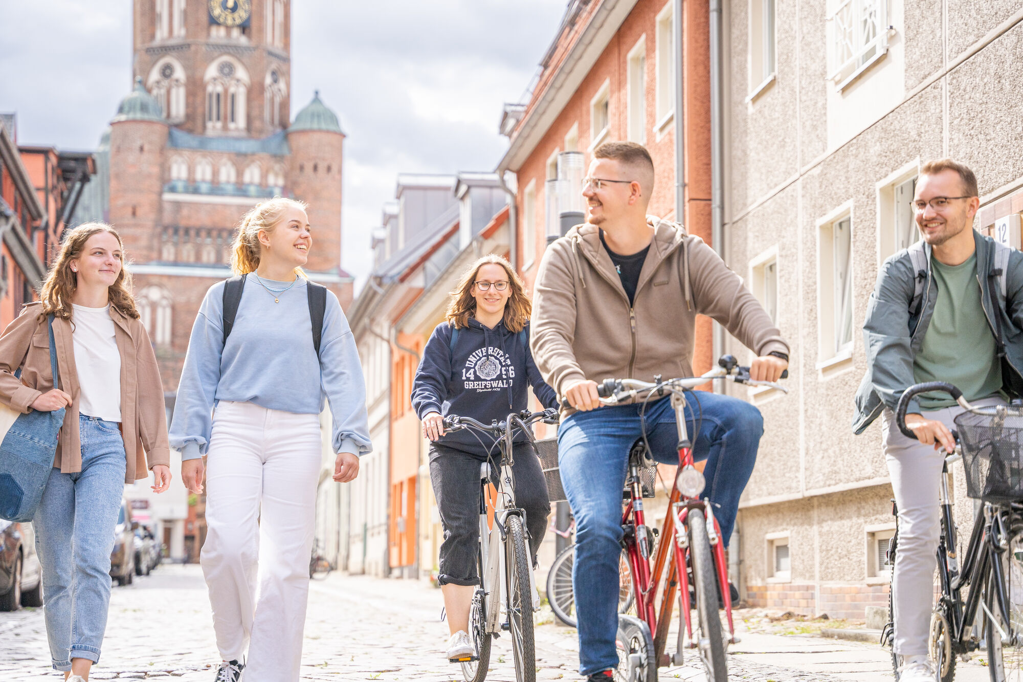 Studierende in der Stadt Greifswald Studierende gehen zu Fuß durch die Hunnenstraße Richtung Campus Loefflerstraße. Im Hintergrund ist der Dom zu sehen.