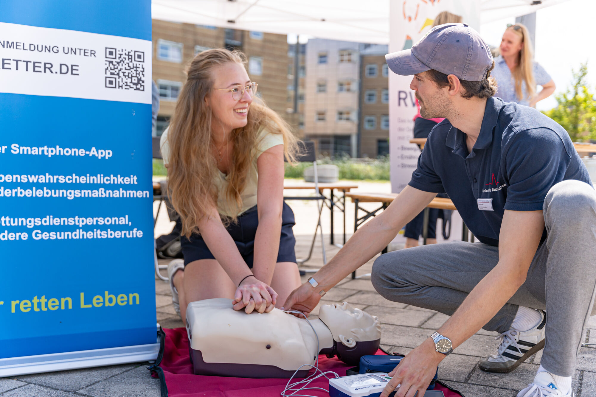 Ein Medizinstudent erklärt an einem Übungskörper, wie eine Herz-Druck-Massage durchgeführt wird.