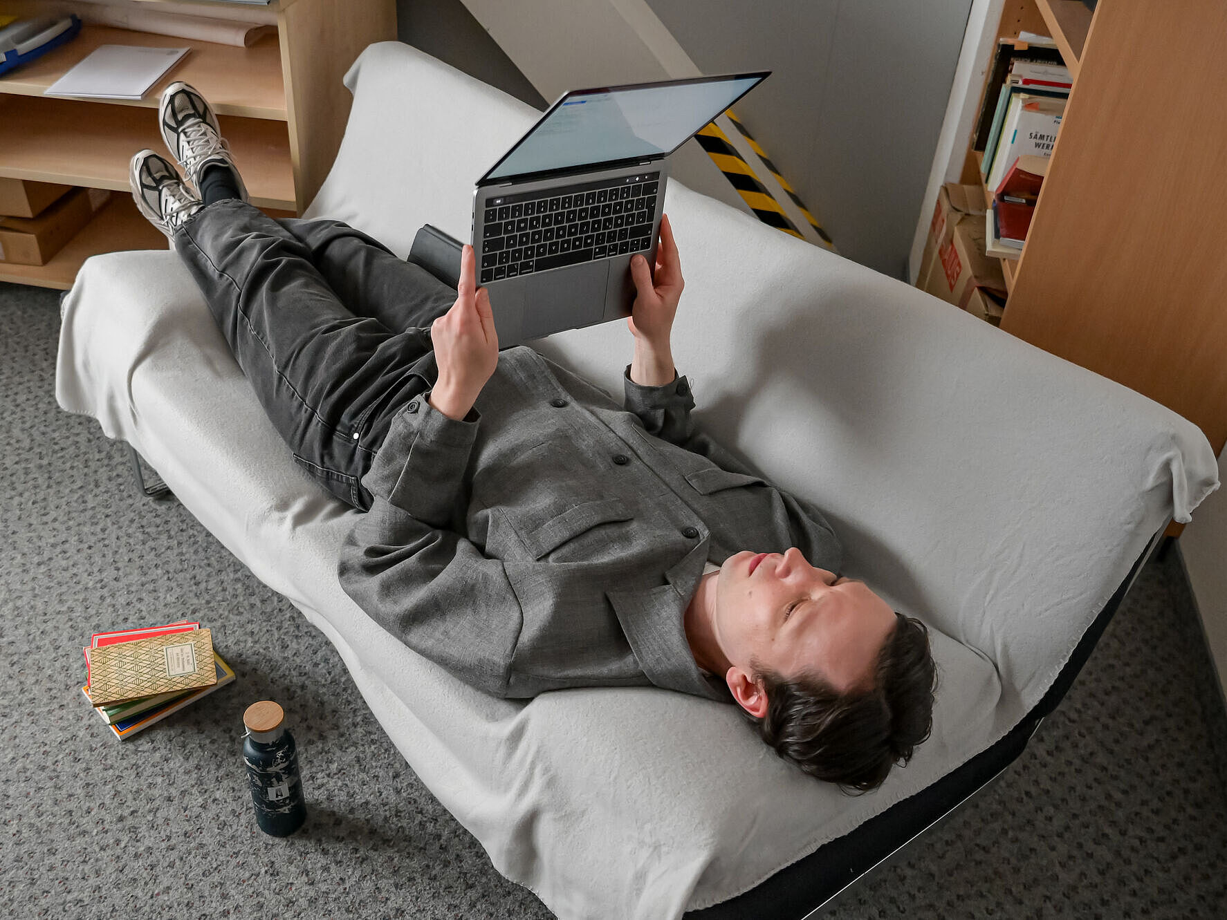 Elias Kreuzmair liegt rücklings auf einer Couch und liest einen Text auf einem Tablet.