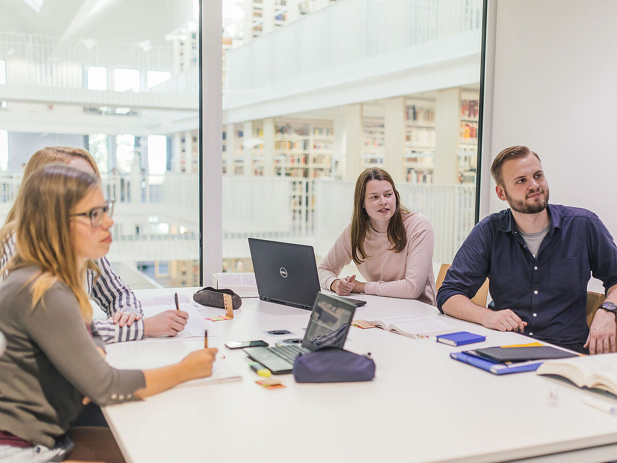 Lernsituation in der Bereichsbibliothek: Vier Personen sitzen in einem Gruppenraum an ihren Notebooks.