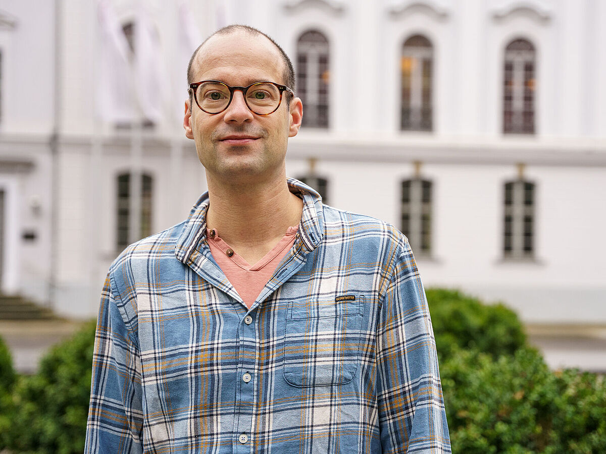 Prof. Dr. Matthias Ludewig steht auf dem Rubenowplatz vor dem Unihauptgebäude.
